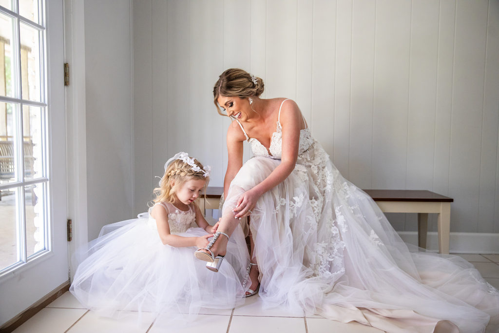 Flower girl helping bride with wedding day shoes