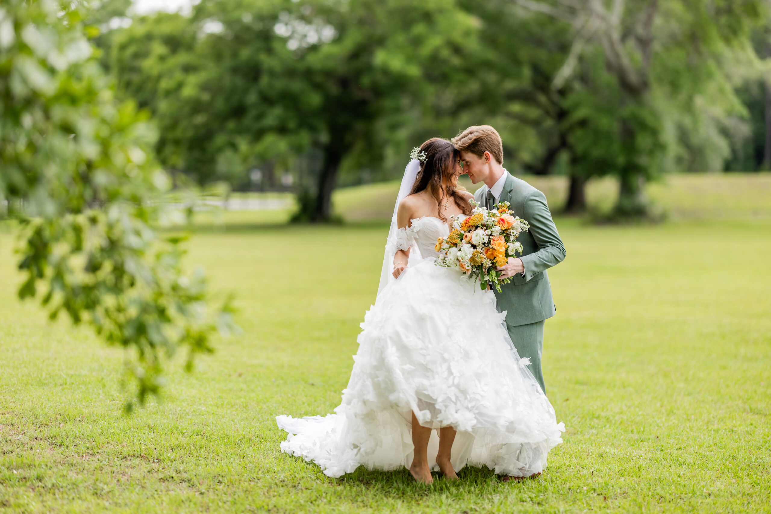 bride and groom in a green field at The Majestic Oaks